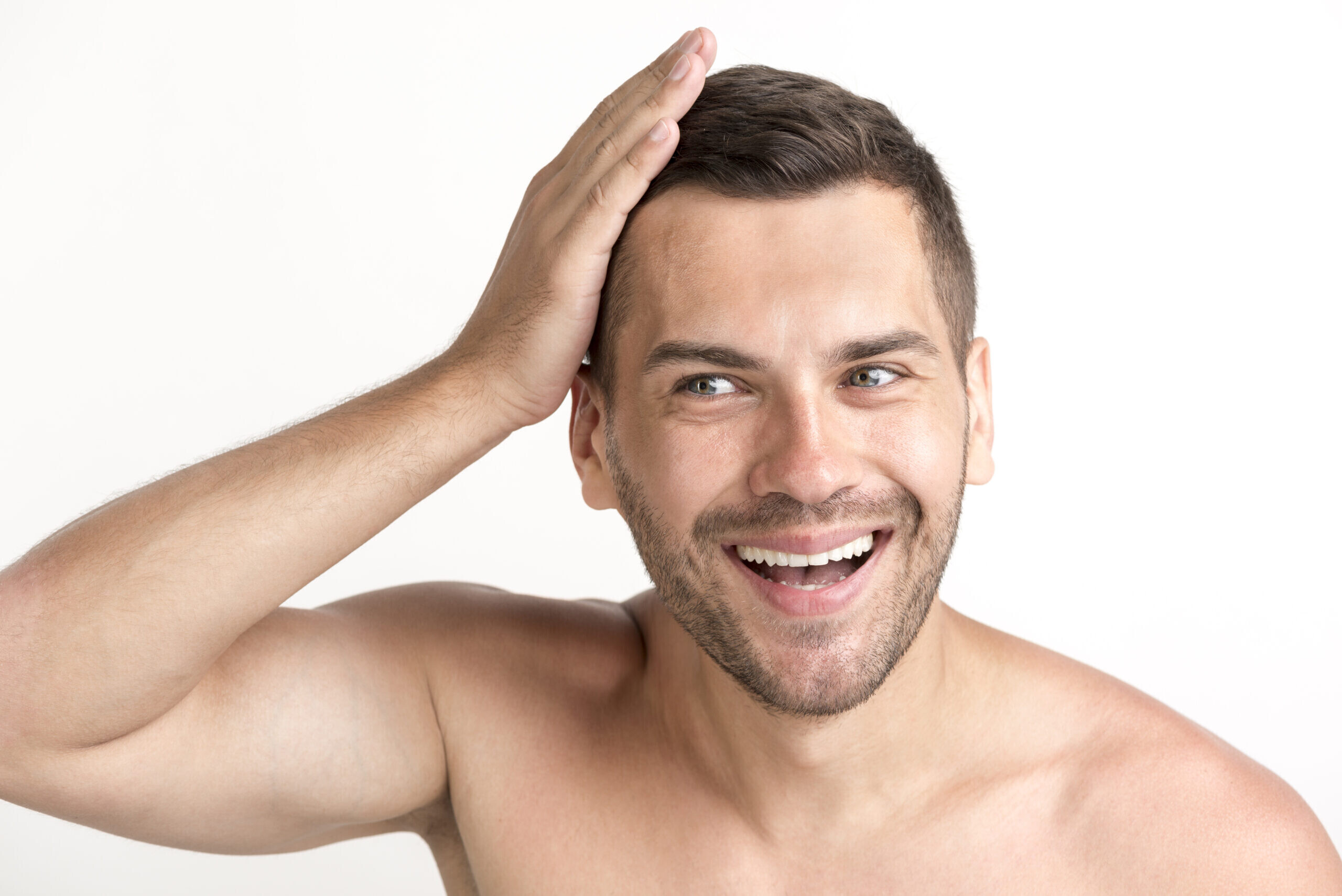 smiling young shirtless man touching his hair white backdrop 1 scaled